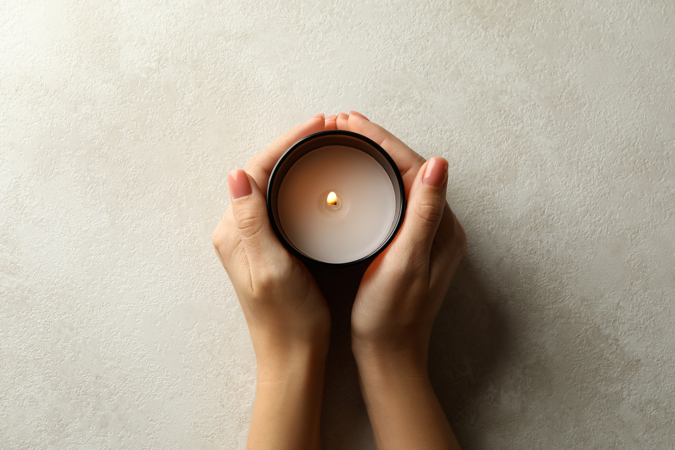 Female hands holding scented candle, top view